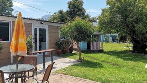 A patio with outdoor furniture, a small table, and a yellow umbrella. - Room-joy's Place - Willy's Cottage - 2 S (Cape Town)