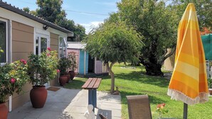 A house with a patio, potted plants, a wooden bench, and a yellow umbrella. - Room-joy's Place - Willy's Cottage - 2 S (Cape Town)