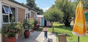 A house with a patio, potted plants, a wooden bench, and a yellow umbrella. - Room-joy's Place - Willy's Cottage - 2 S (Cape Town)