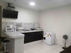Une cuisine équipée d’un four à micro-ondes, d’une cuisinière, d’un réfrigérateur et d’un ventilateur.