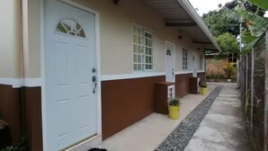 A building with a white door, a window, and a small potted plant on the porch. - Shop-Changuinola-Fit5people (Changuinola)