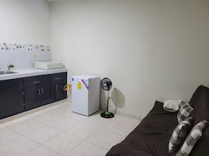 A compact kitchen with a refrigerator, a stove, and a fan.