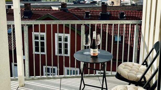 En balkong med ett bord, två stolar och en flaska vin.