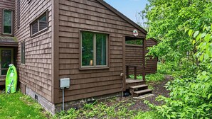 Une cabane en bois brun avec un porche, un kayak vert et un petit jardin.