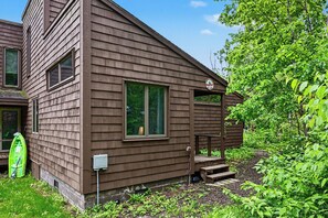 Une cabane en bois brun avec un porche, un kayak vert et un petit jardin.