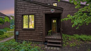 Une cabane en bois avec une véranda, une porte et une fenêtre.