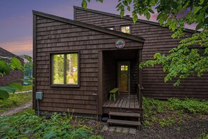 Une cabane en bois avec une véranda, une porte et une fenêtre.