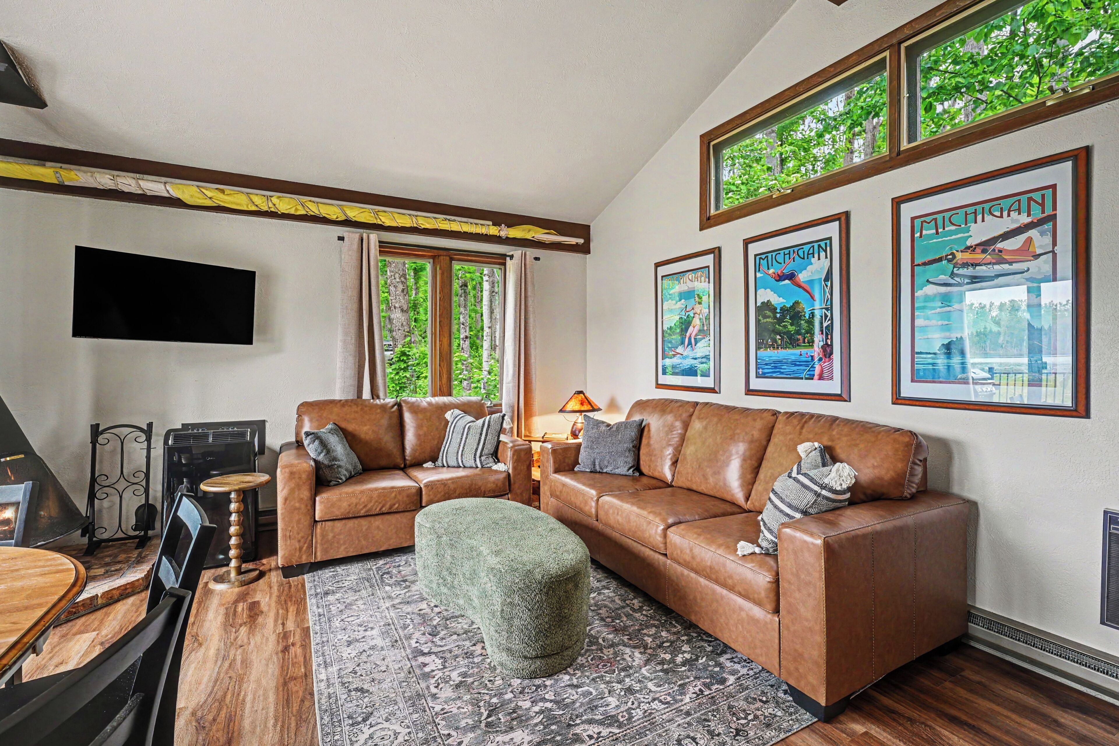 A living room with a sectional sofa, a television mounted on the wall, and framed posters on the wall.. Lakefront Townhome w/ Great Amenities & Kayaks-4 Bedrooms 2 Bathrooms - Sleeps 8