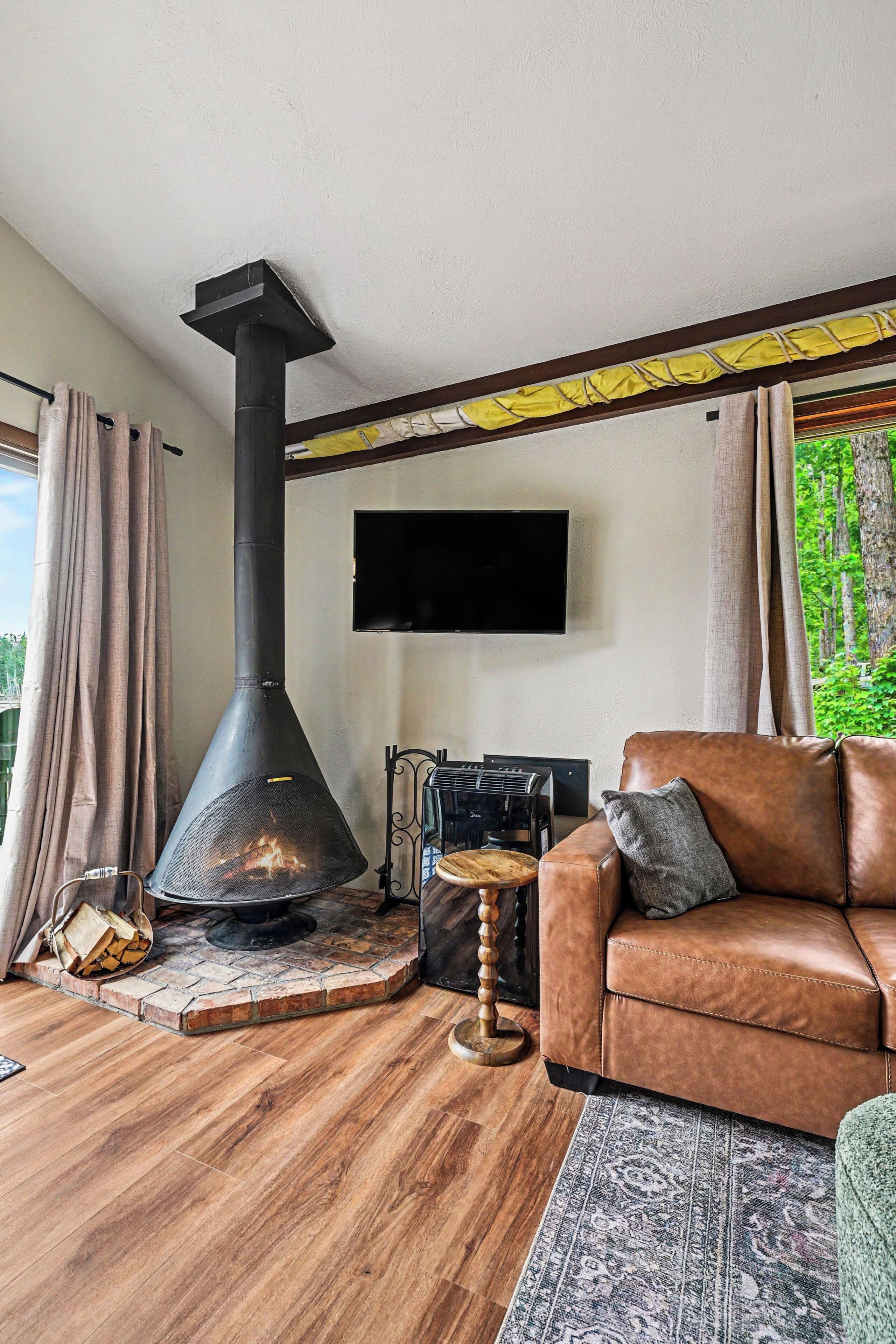 A living room with a fireplace, a sofa, a television, and a view of greenery outside.. Lakefront Townhome w/ Great Amenities & Kayaks-4 Bedrooms 2 Bathrooms - Sleeps 8