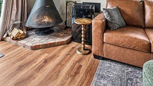 Un salon avec une cheminée, un canapé, un téléviseur et une vue sur la verdure à l’extérieur.