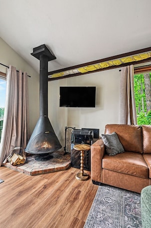 A living room with a fireplace, a sofa, a television, and a view of greenery outside.. Lakefront Townhome w/ Great Amenities & Kayaks-4 Bedrooms 2 Bathrooms - Sleeps 8