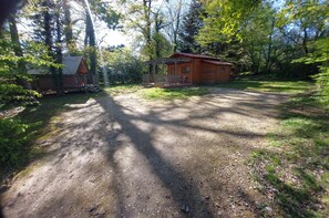 Un chalet rustique dotĂ© dâun porche et dâune petite terrasse, entourĂ© dâune forĂȘt dense.