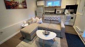 A modern living room with a grey sectional sofa, a white coffee table, and a painting on the wall.