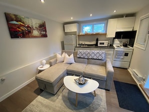 A modern living room with a grey sectional sofa, a white coffee table, and a painting on the wall.