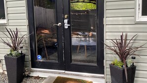 A black double door with a glass panel, a welcome mat, and two potted plants.
