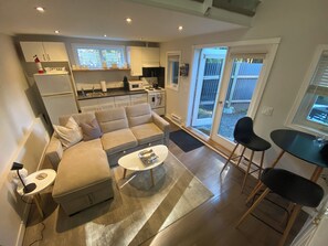A modern living room with a sofa, coffee table, and a dining area with chairs.