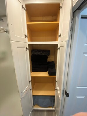 A white wardrobe with multiple shelves and a hanging section.
