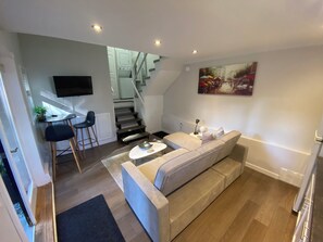 A modern living room with a sofa, coffee table, and a TV mounted on the wall.