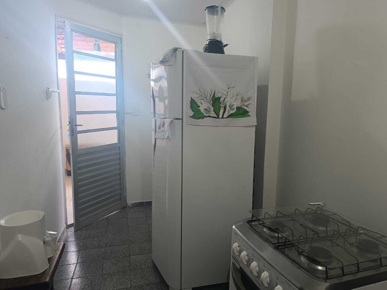 A kitchen with a refrigerator, a stove, and a door leading to another room.