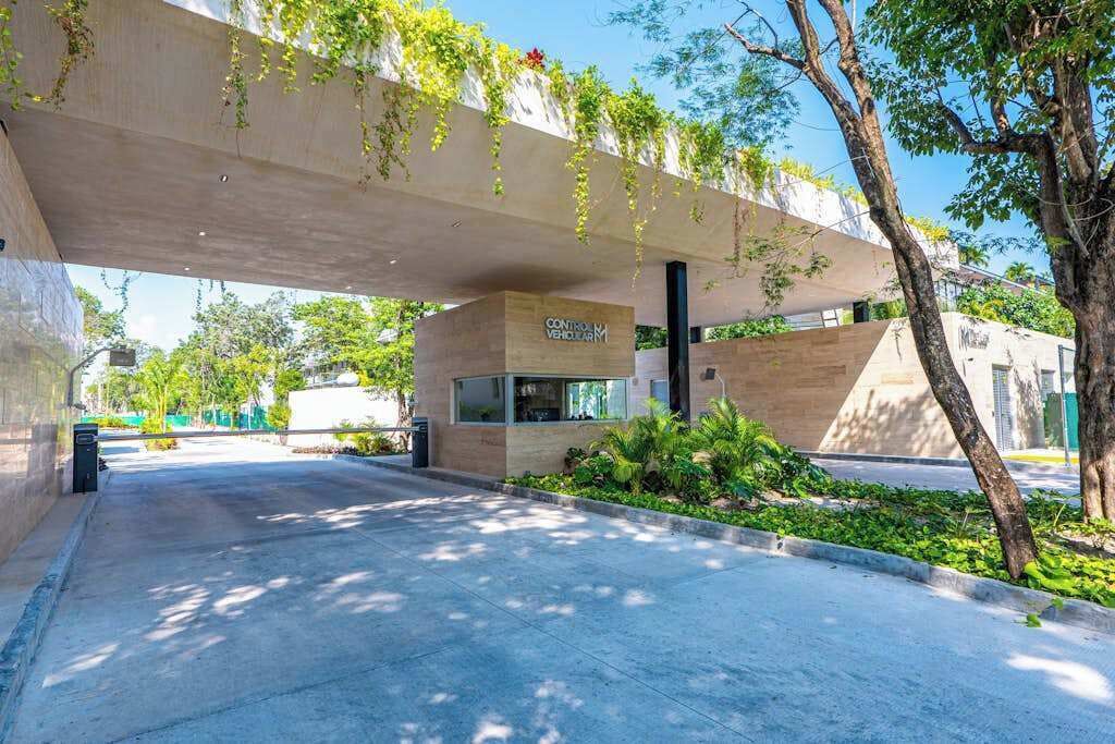 Un bâtiment moderne doté d’une façade en béton, d’une entrée bien visible et d’éléments de verdure.