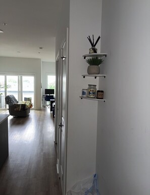 Et moderne køkken med hvide skabe, en indbygget ovn og en bordplade. Der er et spiseområde med et bord og stole, og et stort vindue giver naturligt lys.