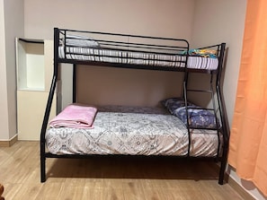 Una cama litera con ropa de cama estampada, una toalla rosa y un pequeño estante.