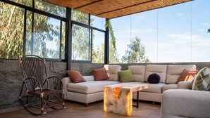 Un área de estar al aire libre con un sofá, una mecedora y una mesa con luz integrada.