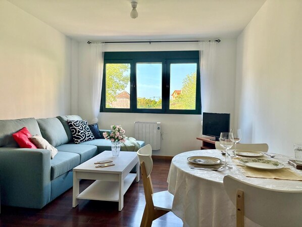 A living room with a sofa, a coffee table, a dining table set for two, and a TV. - * Coastal Paradise: Your relaxing corner by the beach (O Pindo)