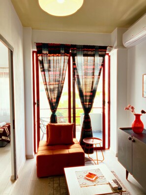 A room with a sofa, a small table, a red vase, and a window with curtains. - Fabulous 11-bedroom hotel in Heart of Shkodër.AC ,High-speed Wi-Fi.Comfort,style (Shkodër)