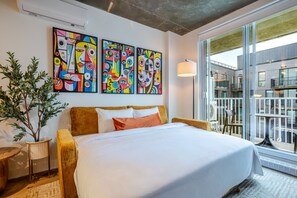 Ein Hotelzimmer mit einem großen Bett, einer Zimmerpflanze und drei abstrakten Bildern an der Wand.