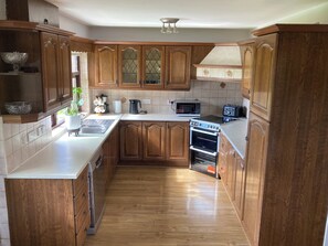 Una cocina con armarios de madera, microondas, tostadora y horno.