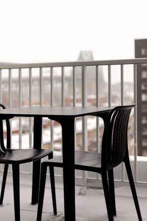 A balcony with a metal railing, a black table, and a black chair. - Montreal Retreat with Rooftop Pool & Parking (Montreal)
