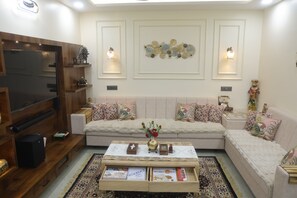 Uma sala de estar com sofá, mesa de centro, televisão e arte decorativa na parede.