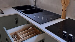 A kitchen with a built-in sink, a countertop with a wooden utensil holder, and a window with blinds. - Luxury Guest Apartment Fully Furnished With all Amenities (Pretoria)