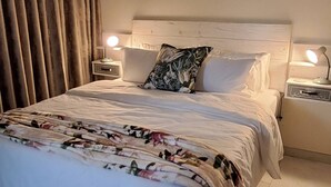 A neatly made bed with a floral bedspread, two bedside lamps, and a ceiling-mounted air conditioning unit. - Luxury Guest Apartment Fully Furnished With all Amenities (Pretoria)