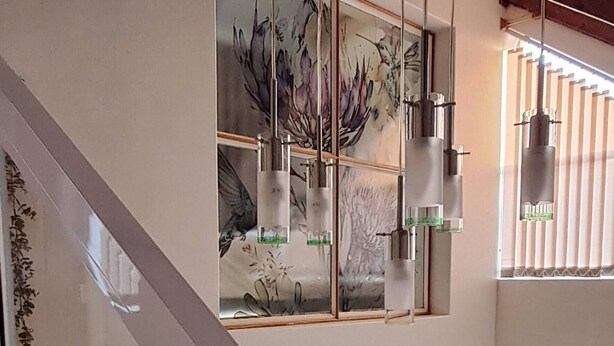 A multi-level interior with a glass staircase, a ceiling fan, and artwork on the walls. - Luxury Guest Apartment Fully Furnished With all Amenities (Pretoria)