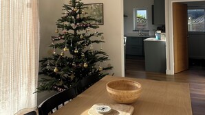 Un comedor con un árbol de Navidad, una lámpara de fibra y vista a la cocina.