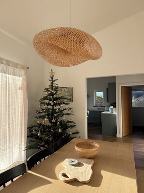 A dining area with a Christmas tree, a woven light fixture, and a view into the kitchen. - The Hideaway, morden 3-bedroom bungalow in Tintagel, Cornwall (Tintagel)
