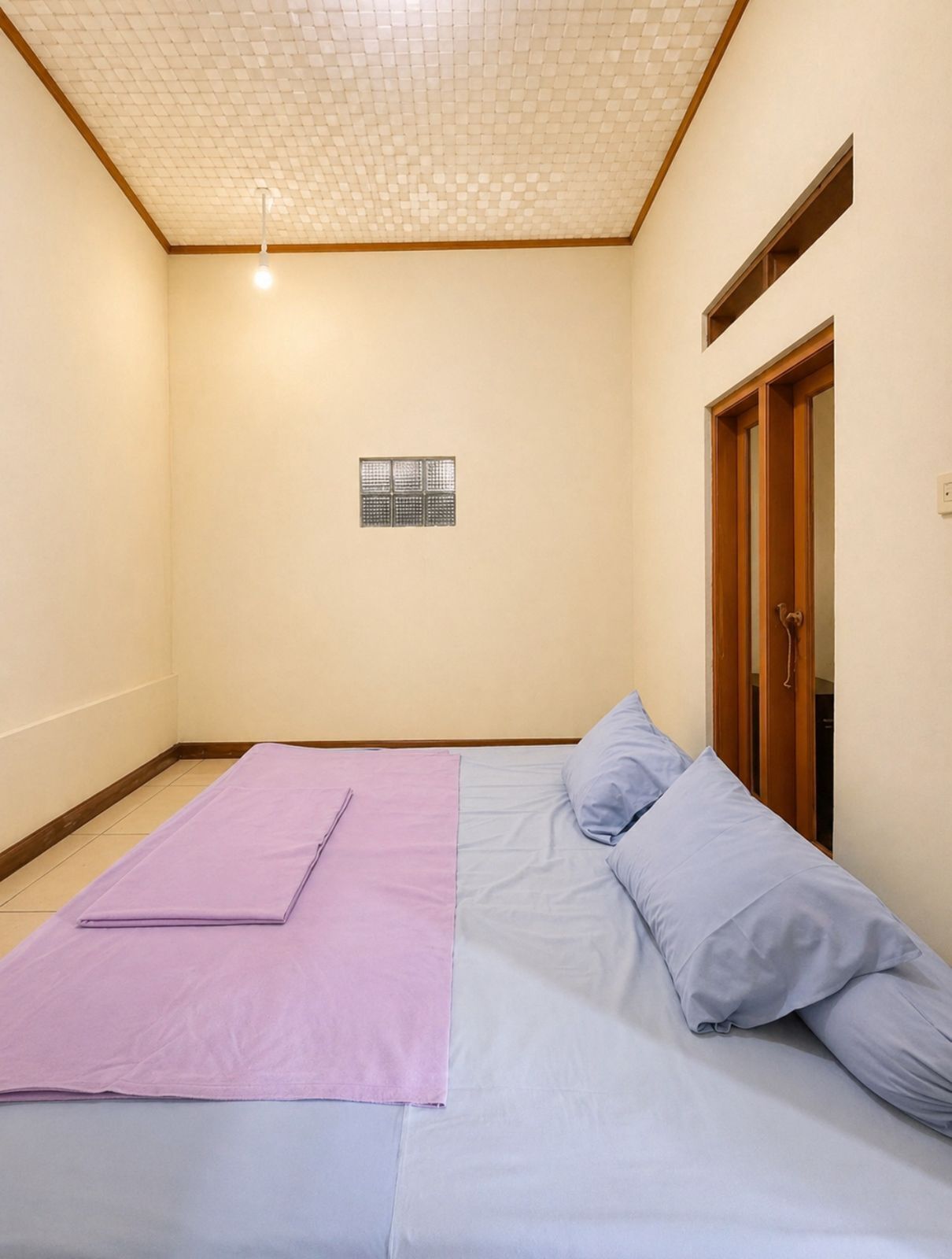 A room with a bed, a small window, and a door.