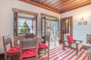 Ein Zimmer mit einem Holztisch und -stühlen, einem rot-weiß gestreiften Teppich und einer Steinwand.