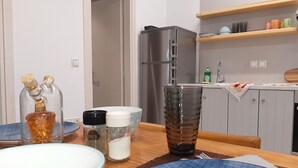 Een moderne keuken met een koelkast, houten planken en een eettafel gedekt met borden en een glas.