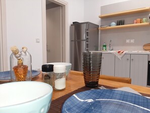 Eine moderne Küche mit Kühlschrank, Holzböden und einem Esstisch, gedeckt mit Tellern und einem Glas.