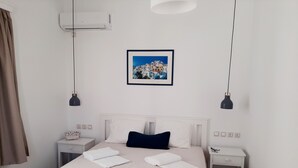 Hotelkamer met een bed, twee nachtkastjes, een wandairconditioner, een ingelijst schilderij en hanglampen.