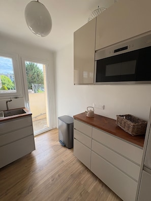 A modern kitchen with a built-in oven, a sink, and a window overlooking a garden. - Bright family apartment in Aix-en-Provence (Aix-en-Provence)