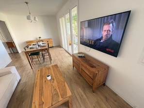 A living room with a wooden dining table, a TV mounted on the wall, and a wooden cabinet. - Bright family apartment in Aix-en-Provence (Aix-en-Provence)