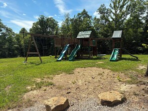 A playground with two slides and a swing set.