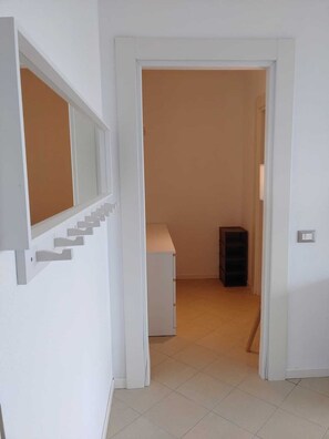 A hallway with a white door, a staircase, and a small cabinet. - BEst16 Relax&SeaView. Seafront, with covered parking space. (SAN LORENZO AL MARE)