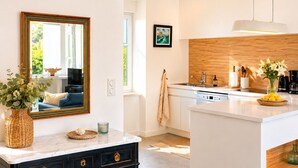 A modern kitchen with a central island, a built-in oven, and a large window. - LocaLise - La clé de l'Océan - House with exceptional sea views (Treffiagat)