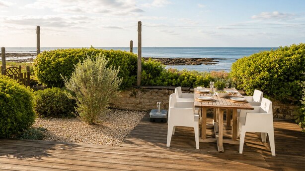 An outdoor dining area with a view of the sea, surrounded by greenery and a wooden deck. - LocaLise - La clé de l'Océan - House with exceptional sea views (Treffiagat)