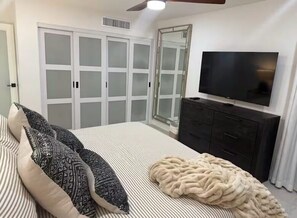 Ein Schlafzimmer mit Bett, Fernseher, Kleiderschrank und einer Schiebetür.